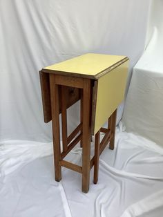 a small wooden table sitting on top of a white sheet