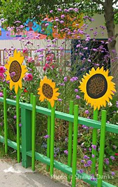 three sunflowers are placed on the green fence