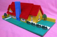 a lego model of a house on a pink background