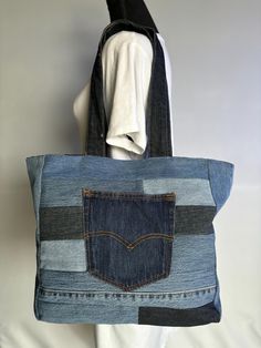 a denim tote bag hanging on a white wall