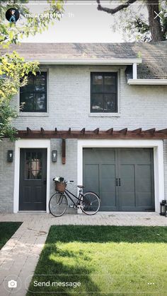 a bicycle parked in front of a house with two garage doors and a pergolated roof