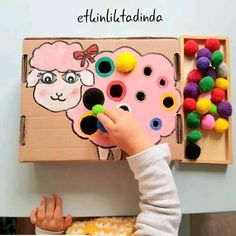 a young child is playing with an animal magnet board and pom - poms