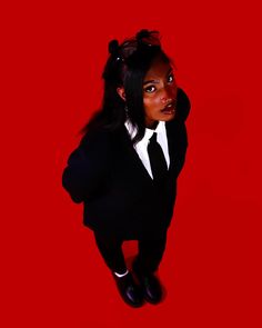 a woman in a suit and tie is posing for a photo against a red background