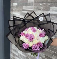 a person holding a bouquet of white and pink roses in front of a brick wall