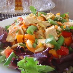 a salad with chicken, carrots and lettuce on a white plate at a restaurant