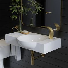 a white sink sitting under a mirror next to a toilet and a plant in a vase