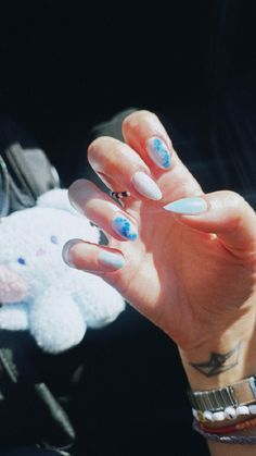 a woman's hand with blue and white nail polish holding up a stuffed animal