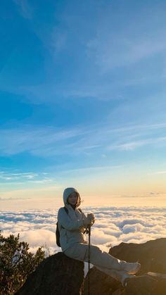 a person sitting on top of a mountain above the clouds