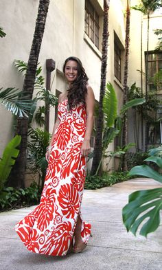 a woman in a red and white dress is standing near some palm trees on the sidewalk