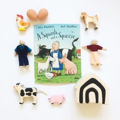 an assortment of toys including farm animals, and a children's book on a white surface