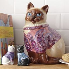 a cat figurine sitting on top of a wooden table next to two books