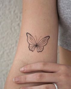 a woman's arm with a small butterfly tattoo on the back of her arm