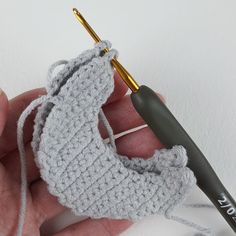 a crocheted object being held in someone's hand with a knitting needle