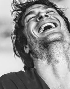 a black and white photo of a man laughing with his eyes wide open while looking up at the sky