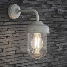 a light that is on the side of a brick wall next to a stone wall