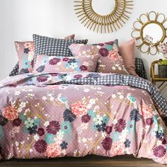 a bed with pink and blue flowers on it in front of a gold sunburst