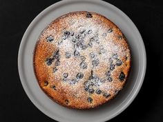 a blueberry cake on a white plate with powdered sugar over the top and bottom