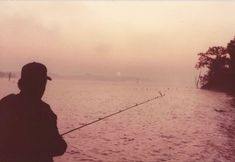 a person fishing on the water at dusk