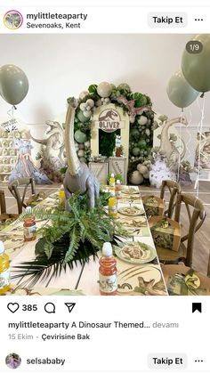 the table is decorated with balloons and greenery for an animal themed birthday party or baby shower