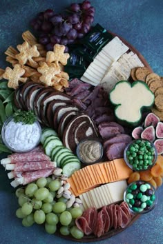 a platter filled with cheese, crackers, grapes and meats is shown