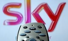 a silver remote control sitting on top of a table next to a sky sign in the background