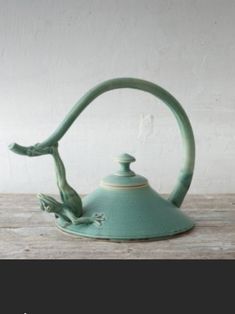 a green tea kettle sitting on top of a wooden table