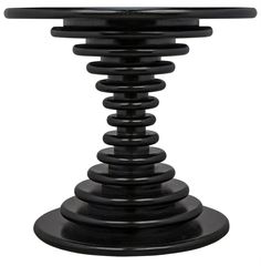 a black table with an oval glass top and spiral design on the base, against a white background