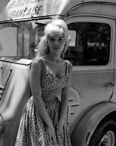 black and white photograph of woman in dress next to truck