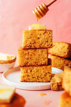 a stack of cake sitting on top of a white plate next to a wooden spoon