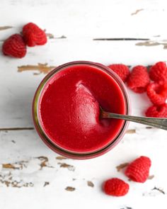 a glass filled with raspberry smoothie on top of a white wooden table