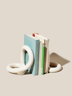 a stack of books sitting on top of each other next to a white book holder