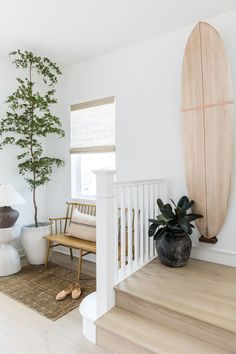 there is a surfboard on the wall in this living room with white walls and wood floors