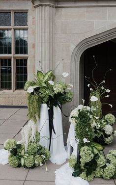 white flowers and greenery in vases on the ground