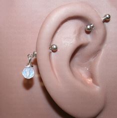 a pair of ear piercings on top of a pink surface