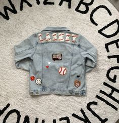 Custom Name or Saying Denim Sports Jacket. Such a fun addition to any Mom's wardrobe during sports season! Using Chenille lettering and patches each jacket is custom and unique. These various and unique patches will be in the chosen sports theme using either MAMA or Last Name specified on back. Jacket Brands are sourced upon size availability in light denim. All patches are adhered with high heat followed with hand stitching to ensure they will be secured. Last Name On Jean Jacket, Baseball Mom Jacket, Baseball Mom Jean Jacket, Baseball Jean Jacket, Letterman Jacket Ideas, Baseball Fits, Denim Patch Jacket, Cursive Embroidery, Letterman Patches