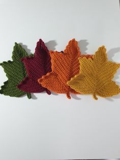 four crocheted autumn leaves on a white surface