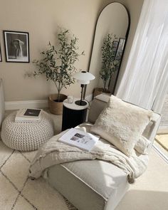 a living room with a bed, mirror and plants in the corner on the floor