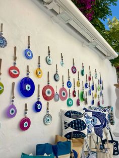 a wall covered in lots of different colored glass items next to a white building with purple flowers hanging from it