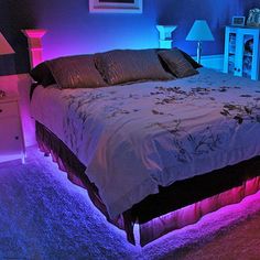 there is a bed with purple and blue lights on the headboard in this room