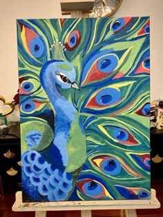 a painting of a peacock on an easel with blue and green feathers painted on it