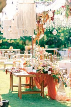 an outdoor table with flowers and chandelier hanging from the ceiling