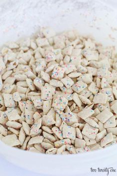 a bowl filled with white dog treats covered in sprinkles on top of a table