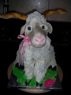 a cake shaped like a sheep with horns on it's head and green grass around its neck