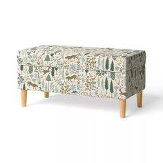 an upholstered footstool with trees and deers on the fabric, against a white background