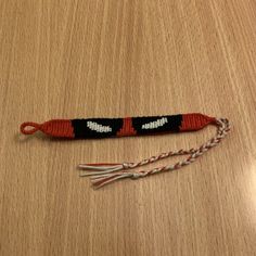 a pair of scissors on top of a wooden table next to an orange and black cord