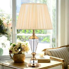 a table lamp sitting on top of a wooden table next to a vase with flowers