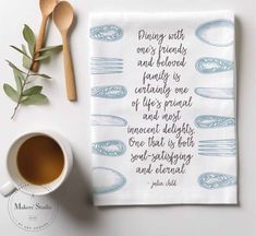 a tea towel with a quote on it next to a cup of coffee and spoons