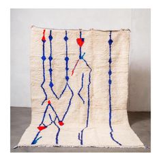 a white blanket with blue and red lines on it, hanging from the wall next to a gray floor