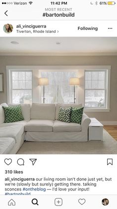 a living room with white couches and green pillows on the top right hand corner