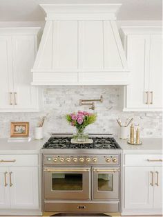 a stove top oven sitting inside of a kitchen next to white cabinets and counter tops